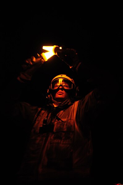 File:US Navy 090919-N-6538W-446 Aviation Boatswain's Mate (Handling) 3rd Class Cory Stallings, from Chicago, Ill., uses yellow flashlights to signal an aircraft to hold position prior to launching.jpg