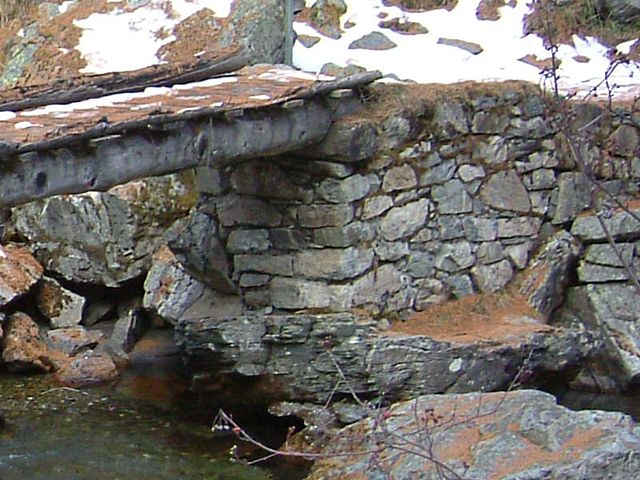 Dry set masonry supports a rustic log bridge, where it provides a well-drained support for the log (which will lengthen its service life).