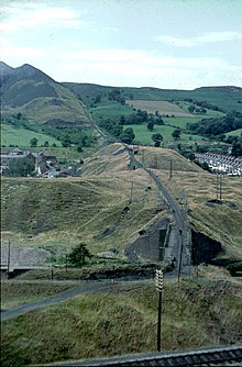Aberfan Colliery spoil tramway before the disaster, with spoil heaps at top left. The red brick building at mid-left is Pantglas County Secondary School. Aberfan Colliery spoil tramway - geograph.org.uk - 73636.jpg