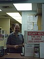 Ticket agent at counter in Niagara Falls Transit Terminal. Smiles are free.