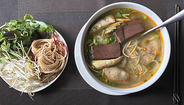 Bún bò Huế, a spicy, lemongrass rice vermicelli noodle soup served with fresh herbs and vegetables