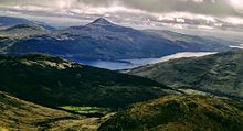 vue panoramique d'un lac entouré de montagnes, avec jeux de lumière