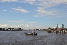 A man and boy fish the Atlantic Intracoastal Waterway in front of Seabreeze. The Carolina Beach Yacht Basin (or Boat Basin) is in the background in the middle. The buildings to the left are on the north end of Carolina Beach. CBfromSeabreeze.jpg