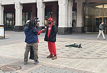 Dos reporters, un d'ells amb una càmera, entrevisten Smalls davant de l'edifici de l'NLRB, on es va fer el recompte de vots.