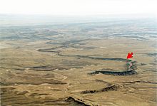 An exhumed river channel (red arrow) in the Cedar Mountain Formation near Green River, Utah Exhumedchannel.jpg