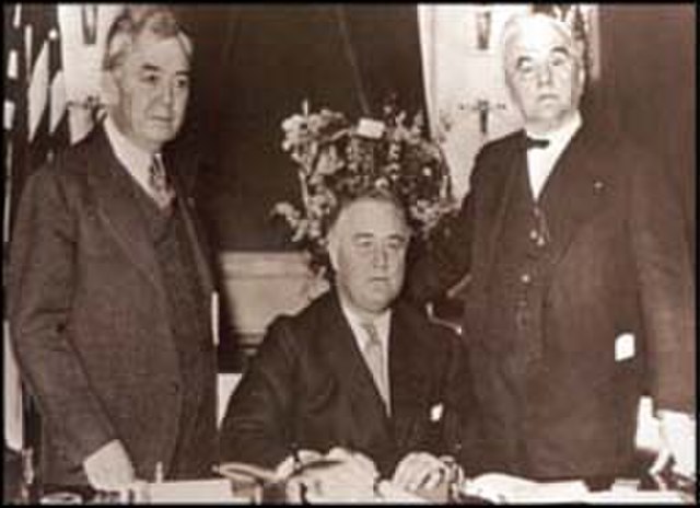 FDR (center) signs the Rural Electrification Act with Congressman John E. Rankin (left) and Norris (right)