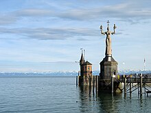 Die Imperia an der Hafeneinfahrt am Bodensee, im Hintergrund die Alpen