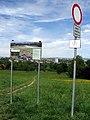 Schönbergwiesen mit Tafel zum Landschaftschutzgebeit in Freiburg-Sankt Georgen, am linken Bildrand die roten Dächer des Augustinums