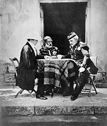 Trois hommes en uniformes militaires autour d'une petite table recouverte d'une nappe