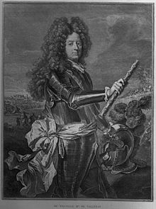 Debout, représenté jusqu'aux genoux, avec son bâton de maréchal dans la main droite, devant un paysage de batailles. Grande perruque. Revêtu d'une armure. Main gauche posée sur son casque.
