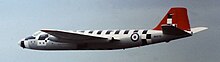Wide view of jet aircraft: The fin is red; short black stripes running perpendicular to and on top of the fuselage.