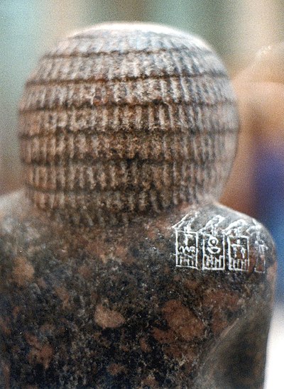 Statue of Hotepdief, priest of the mortuary cults of the first 3 rulers of the dynasty, Hotepsekhemwy, Nebra and Nynetjer. The serekh of Nebra is the middle one on the shoulder of the priest. 2nd Dynasty.jpg