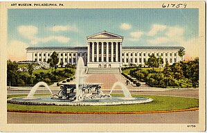 A color postcard showing a large building with classical Greek columns in the background and a fountain in the foreground