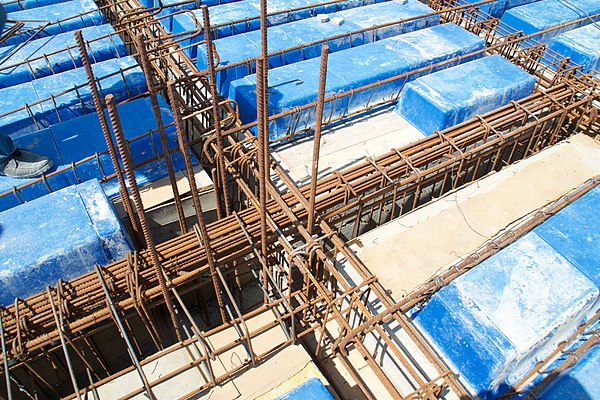 Rebar has been placed atop a temporary wooden formwork deck prior to pouring concrete. The large horizontal rebar "cages" will be encased within a bea