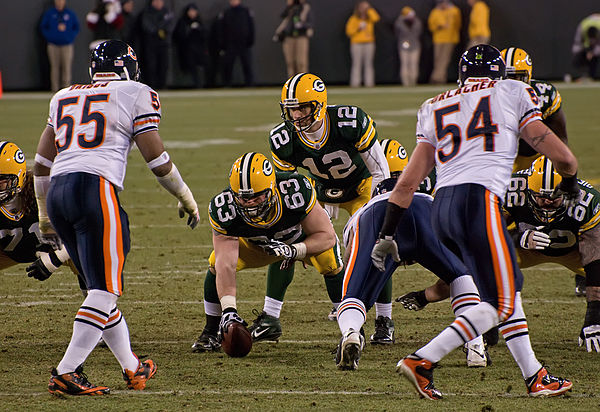 In white jerseys, Lance Briggs (#55) and Brian Urlacher (#54) of the Chicago Bears, are positioned as linebackers on Lambeau Field in 2011.