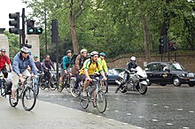 Cyclists use a segregated cut through of a busy interchange in London at rush hour. Cyclists at Hyde Park corner roundabout in London.jpg