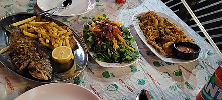 Deep-fried shrimps/calmari, grilled sea beamer fish and a traditional rocket salad at a local "fish shop" ("masmakeh"). Such meals are freshly-prepared all over the city's fishmarket ("Souq As-Samak").