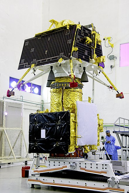 Vikram lander mounted on top of orbiter inside cleanroom.