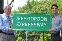 Secretary of the North Carolina Department of Transportation Gene Conti and NASCAR driver Jeff Gordon unveiling a sign for the Jeff Gordon Expressway Jeff Gordon Expressway sign unveiling.jpg