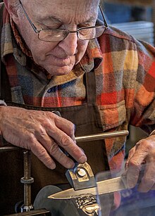 Knife and scissor grinder sharpening a knife on a water-cooled grinding wheel, 2018. Knife Grinder, Topsham (Maine), 2018-01.jpg