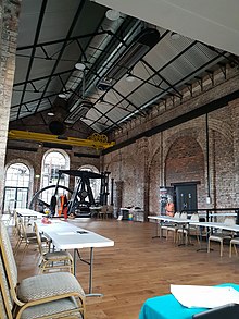 Interior of the national mining museum of Scotland. It is a large brick hall with soaring metal beams supporting the roof. It is set with tables for an event as part of the Midlothian Science Festival.