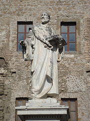 Statue d'un homme debout portant un livre ouvert dans sa main gauche.