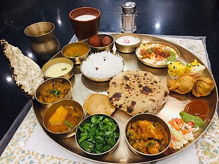 Traditional Indian thali served in Kansa metal thali with various sidedishes for rice, roti and puri.