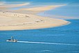 Un bateau ostréicole navigue dans la passe sud entre la dune du Pilat et le banc d’Arguin sur lequel se promènent des plaisanciers.