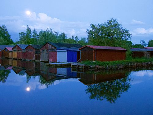 Full moon rising above boathouses