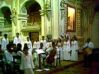 Un chœur et des musiciens vêtus de robes blanches à l'intérieur d'une église.