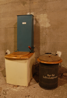 Example of a historical dry toilet with peat dispenser which was used in bunkers during World War II in Berlin (Metroclo by Gefinal) Dry toilet with peat dispenser (Torfstreu-Trockenklosett in German) on display in a former bunker in Berlin.png