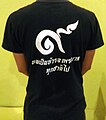 Het Thaise cijfer 9 (๙) dat je overal in Thailand tegenkomt. Hier op een t-shirt, maar ook in sieraden die worden gedragen en in bloemversieringen.