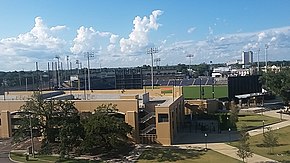 Un estadio de béisbol en la distancia detrás de un estacionamiento de concreto bronceado