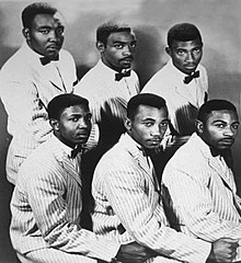 Maurice Williams and the Zodiacs facing the right but looking straight in two rows of three in striped suits and black bow ties.