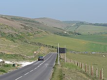 Military Road near Compton Farm (ahead). Automatically in the event of a landslide, or manually in very poor weather, the sign (to the right here) can be illuminated to close the road at this vulnerable point. Military Road at Compton Farm Isle of Wight.jpg