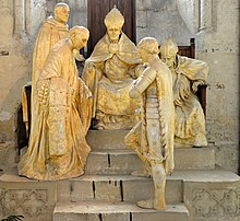 Joan in the foreground, facing figures from her rehabilitation trial in the Monument Commemorating the Rehabilitation of Joan of Arc, a plaster work by Emile Pinchon [fr] (1909, Cathedrale Notre-Dame de Noyon) Monument commemoratif de la rehabilitation de Jeanne d'Arc.jpg