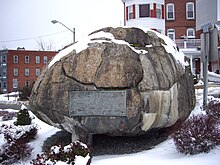 a boulder partially covered in snow with a large plaque on it.