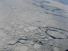 Cette image est une photographie aérienne sur laquelle on peut voir une parie de la côte du Labrador et de l'océan Atlantique en hiver. De nombreuses masses de glace plus ou moins proches les unes des autres recouvrent presque entièrement la surface de l'eau, rendant la navigation difficile.