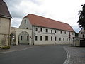 Stable house (No. 1), archway (with two baffle stones) and side building (No. 1a) of a former four-sided courtyard