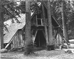 Photograph of a log, A-frame building in a forest setting