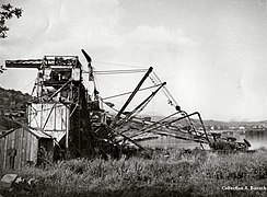Foto antiga em preto e branco mostrando uma escavadeira abandonada.