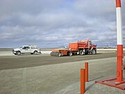 Applying material to bind the gravel and reduce dust. The gravel is packed after the application.