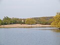 Der Hauptstrand des Seengebietes Binsfeld an der Nordseite des gleichnamigen Sees. Auf dem Strand steht eine Gruppe Tauerweiden. Das flache sandige Nordufer des Binsfeld ist heute der am stärksten frequentierte Badestrand. Dort befindet sich auch ein Kiosk und eine Toilettenanlage. An dessen Standort war bis zum Ende des Kiesabbaus das Kieswerk.