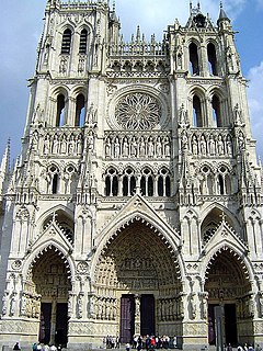 Amiens Cathedral in northern France, showing three portals with wimperg and pinnacles and a rose window.