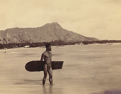 Charles Kauha wearing the malo at Waikiki Beach carrying one of the last Alaia surf boards. Photograph by Frank Davey, 1898.