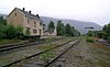 Overgrown tracks running through the picture with a pink, wooden station building to the left