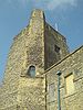 A tall stone tower, seen from below, against a blue sky.