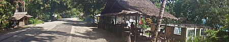 Hot food stall cooking sausages. House ruins (R) from tension era arson