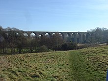 stone viaduct with multiple arches, partly obscured by trees
