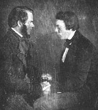 Phineas Parkhurst Quimby (left), briefly a follower of Poyen, putting Lucius Burkmar in a trance. Phineas Quimby and Lucius Burkmar.jpg